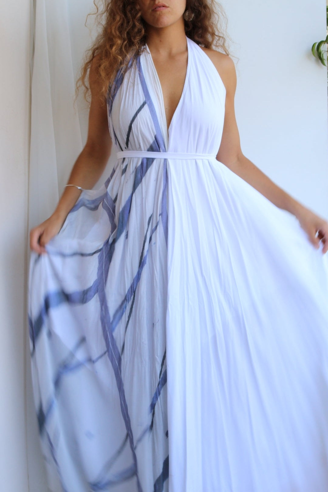Woman wearing a white dress with blue abstract patterns against a white background